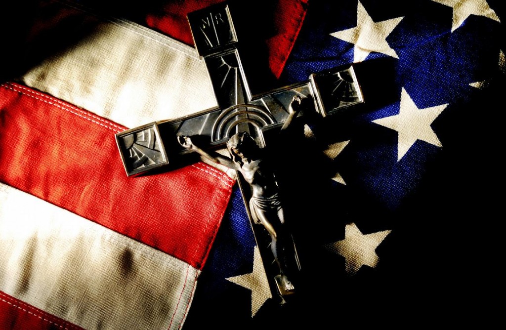 The U.S. flag and a crucifix are pictured in an illustrative photograph. Pope Benedict XVI in a talk to a group of visiting U.S. bishops Jan. 19 echoed the bishops in their concerns over extreme secularism and threats to religious freedom in America. (CNS photo/Mike Crupi, Catholic Courier) (Jan. 19, 2012) See POPE-US Jan. 19, 2012.